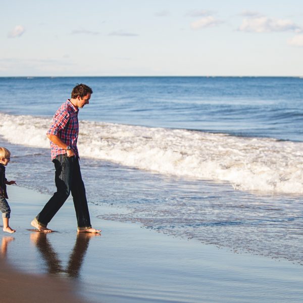 A father and child walking along the beach