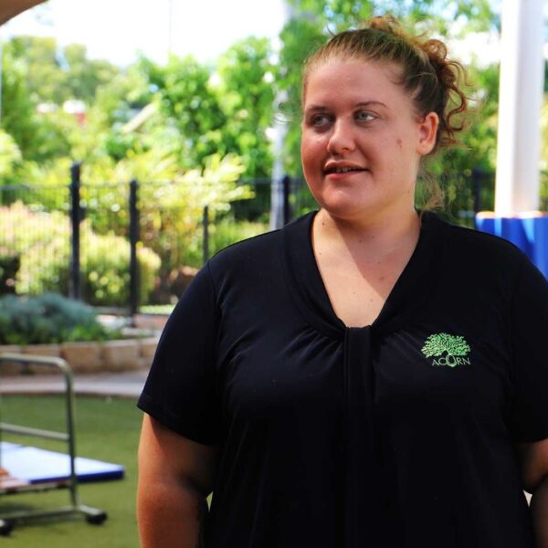 Image shows a young woman wearing black shirt with a green logo.